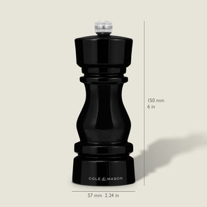 A Cole & Mason London Black Acrylic Pepper Mill (150mm tall, 57mm wide) from the Salt & Pepper Mills collection stands upright on a light background, casting a faint rightward shadow and featuring adjustable grind settings.
