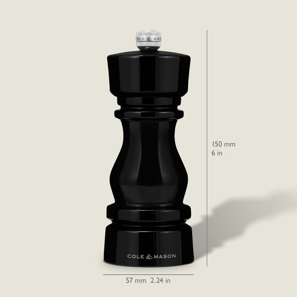 A Cole & Mason London Black Acrylic Pepper Mill (150mm tall, 57mm wide) from the Salt & Pepper Mills collection stands upright on a light background, casting a faint rightward shadow and featuring adjustable grind settings.