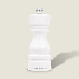The Cole & Mason London White Acrylic Salt & Pepper Mill (150mm) with adjustable grind stands upright on a light beige background—an elegant, modern addition to any kitchen.