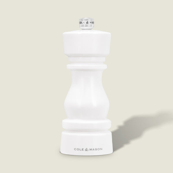 The Cole & Mason London White Acrylic Salt & Pepper Mill (150mm) with adjustable grind stands upright on a light beige background—an elegant, modern addition to any kitchen.
