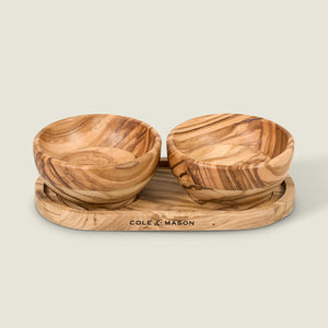 The Cole & Mason Portobello Olive Wood Serving Board & Pinch Pot Set features two small olive wood pinch pots with natural grain, sitting side by side on a matching board, all against a plain light background.