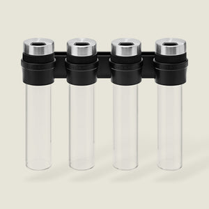 The Cole & Mason Shadwell Slim-Mount Spice Storage features four clear airtight glass containers with silver lids in a vertical black wall rack—ideal for stylish herb and spice storage.