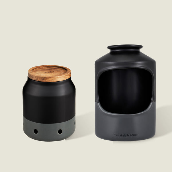 The Cole & Mason Elmdon Garlic Keeper & Strethall Salt Pig Set includes a matte black and gray ceramic garlic keeper with vent holes and a wooden lid, plus an open-front salt pig, both shown against a neutral background.