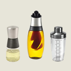 The Cole & Mason 3 Piece Oil & Vinegar Set features kitchen pourers with silver lids—one short and round, one with yellow liquid, and one marked for measurements, making it a stylish bundle of essentials.